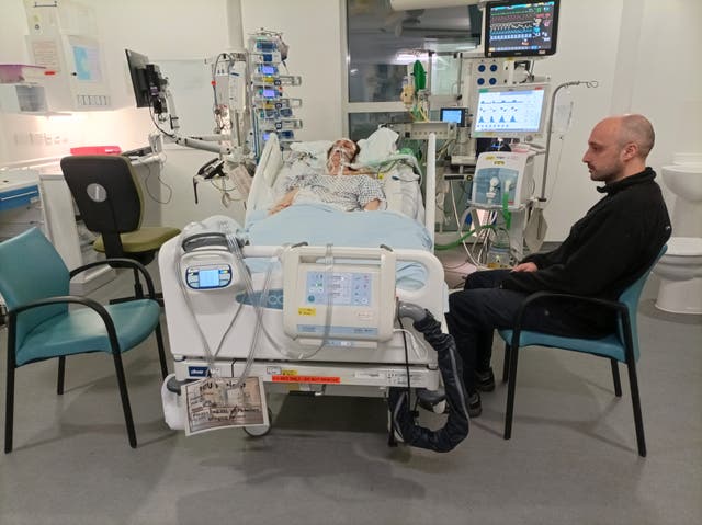 <p>Anna Chithrakala in a coma in the ICU with her brother Ruben sitting with her</p>