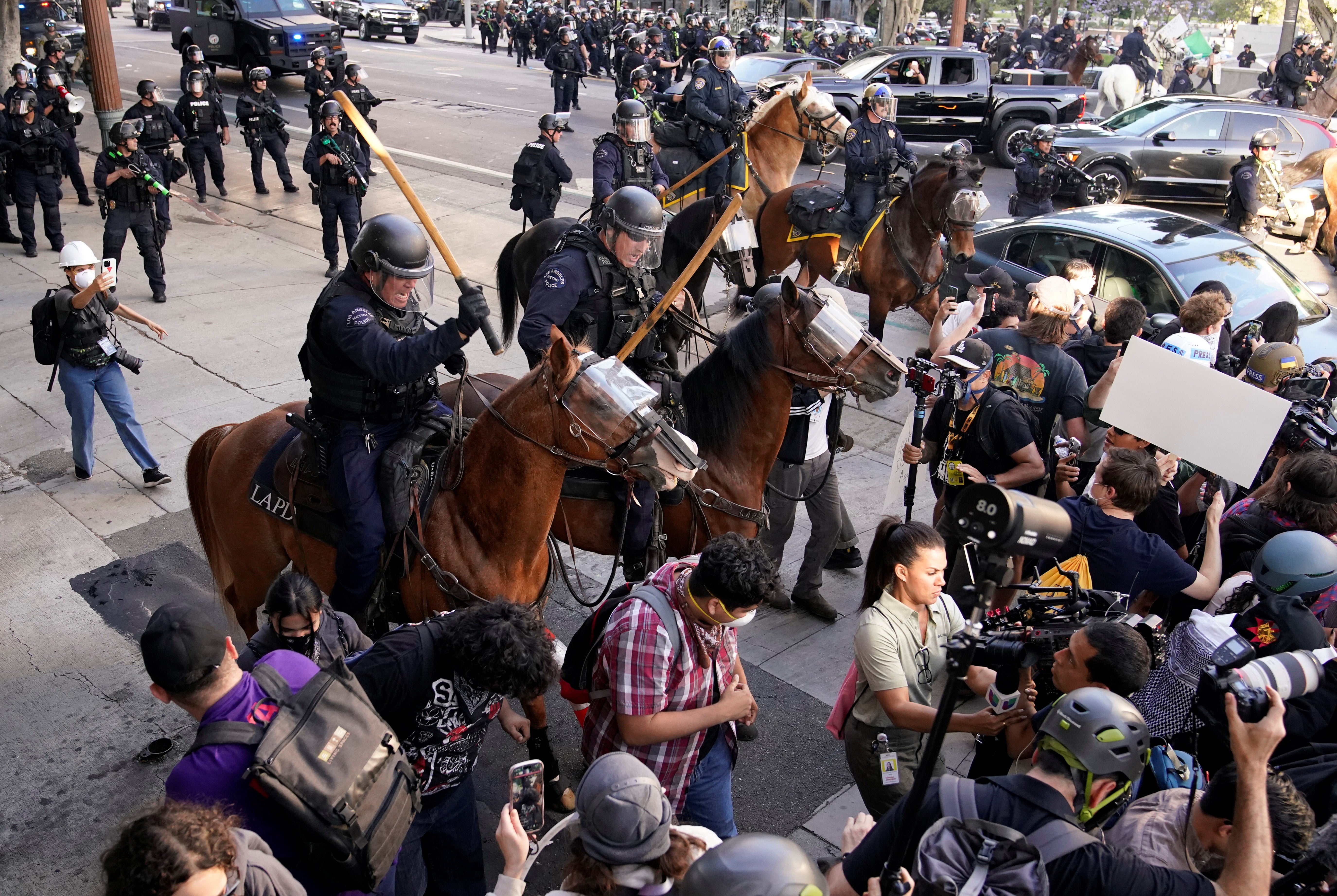 Police officers ride horses as they attempt to disperse protesters demonstrating against federal immigration sweeps in downtown Los Angeles